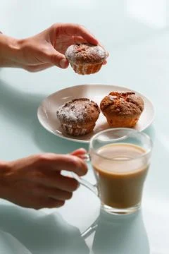 Close up of hands taking one of three curd muffin, and holding glass cup of.. Stock Photos