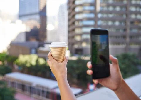A close up of hands taking a picture of her coffee on city balcony Stock Photos