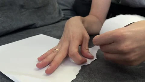 Close-up of hands tearing a small piece from a white sheet of paper Stock Footage 336524169