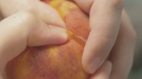 Close up of hands tears a peach in two pieces Stock Footage 134069443
