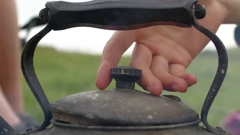 Close up on hands tending to old fashioned kettle Stockbeeldmateriaal 84899944
