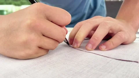 Close-Up of Hands Tracing Pattern Line with Marker on Light Fabric 動画素材 346499401