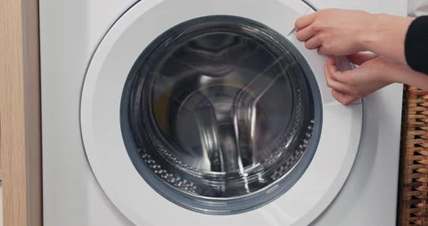 Close-up of hands trying to open the door of the washing machine, which is Stock Footage 218479256