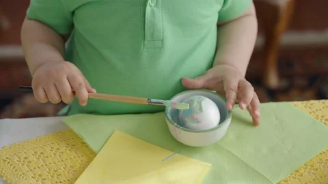 Close-up of hands trying to paint Easter egg with paint and brush Stock Footage 177920027
