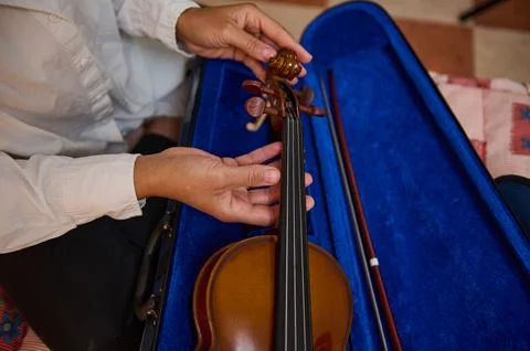 Close-up of hands tuning a violin with bow in blue case Stock Photos