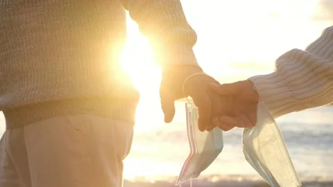 Close up of hands of two people holding each other with their mask to protect of Stock Footage 151332869