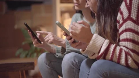 Close-up of the hands of two women using a smart phone together at home. Online Stock Footage 169378473