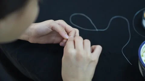Close-up of Hands Tying a Knot with Clear Thread for Jewelry Making Vídeos de archivo 333562860