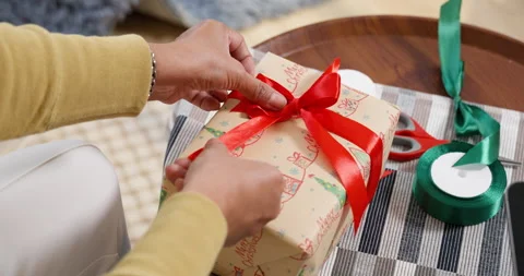 Close-up of hands tying a red ribbon on a Christmas gift with festive wrapp.. Stock Footage 288113107