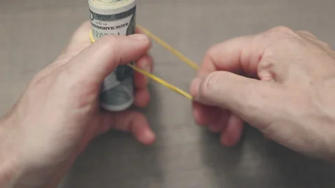 Close-up of hands tying rolled up dollar bills with yellow rubber band Stock Footage 160705775