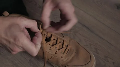 Close-up hands tying shoelace on brown leather sneaker Stock Footage 341365373