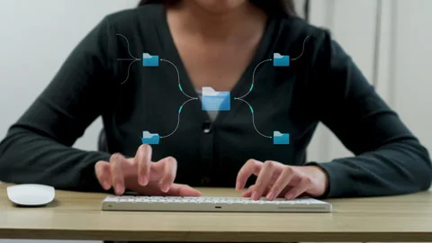 Close-up of hands typing and using mouse with animated central file structure Stock Footage 347183656
