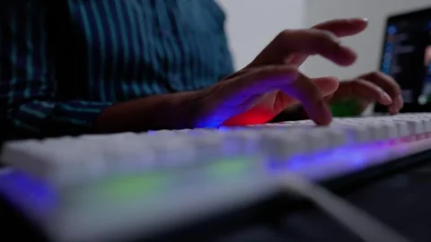 Close-up of hands typing on a backlit keyboard with a laptop in the backgroun Stock Footage 320725108