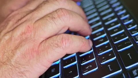 Close-up of hands typing on a backlit laptop keyboard in an office Stock Footage 348488674