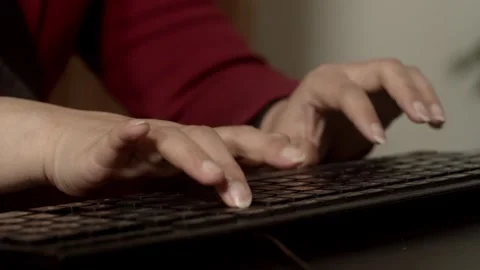 Close-up of Hands Typing on Black Keyboard in Warm Light Vidéo 334708785