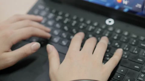 Close up of hands typing on a black laptop keyboard in a bright office work.. Stock Footage 347410346