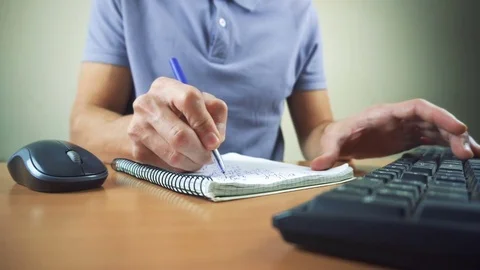 Close up of hands typing on computer keyboard and mouse. Writing in notebook Stock Footage 84497296