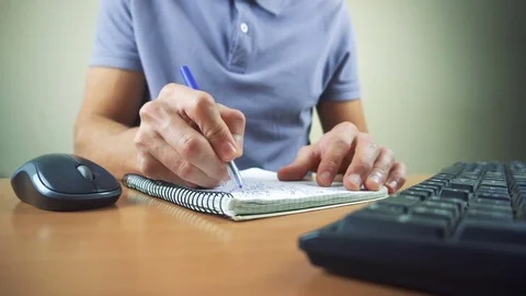 Close up of hands typing on computer keyboard and mouse. Writing in notebook Stock Footage 84497481