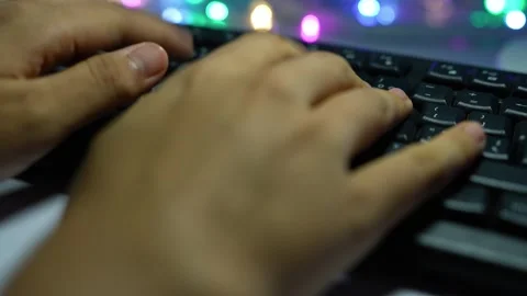 Close-up of hands typing on a computer keyboard with colorful blurred light.. Vídeos de archivo 337899316