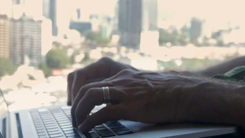 Close up of hands typing on a computer laptop keyboard overlooking a city Video stock 86658520