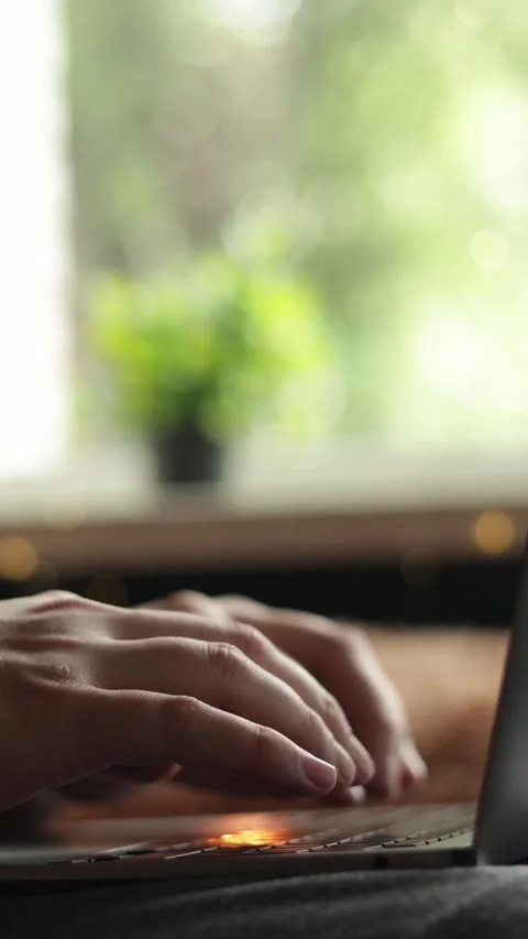 Close-up of hands typing on a laptop with a blurred green background Stockbeeldmateriaal 343838022