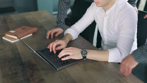 Close-up of hands typing on a laptop in a busy office with multiple devices Stock Footage 305405957