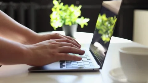 Close-up of hands typing on a laptop with a coffee cup nearby Vidéo 342280458