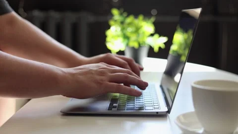 Close-up of hands typing on a laptop with a coffee cup nearby Stockbeeldmateriaal 342280514