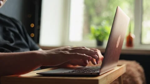 Close-up of hands typing on a laptop computer near a window Stock Footage 340264885