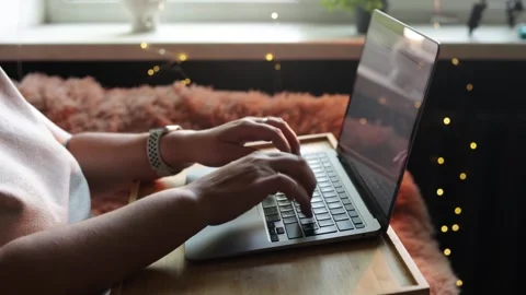 Close-up of hands typing on a laptop with cozy, warm lighting and bokeh effects Stock Footage 340265244