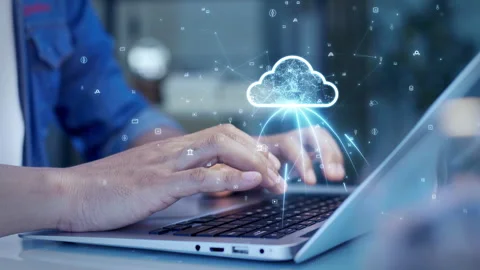 Close-up of hands typing on a laptop with a digital cloud icon overlay, represen Stock Footage 306152943