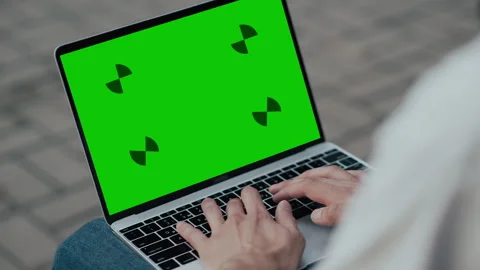 Close up of hands typing on a laptop with green screen outdoors on paved surface 库存影片 339215837