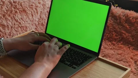 Close-up of hands typing on a laptop with a green screen on a cozy blanket Stock Footage 340265184
