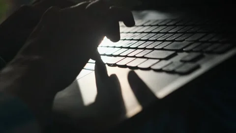 Close-up of hands typing on laptop keyboard on dark blurred background. Stock Footage 241759849