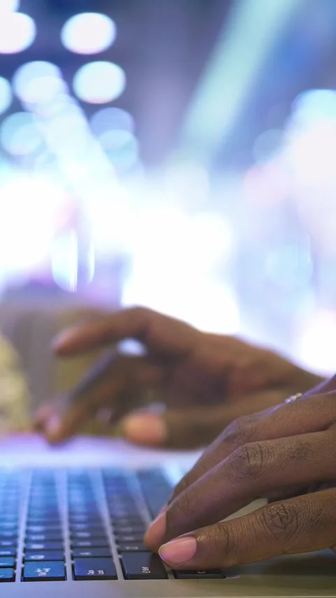 Close-up of hands typing on a laptop keyboard with blurred lights in the Stock Footage 313259109