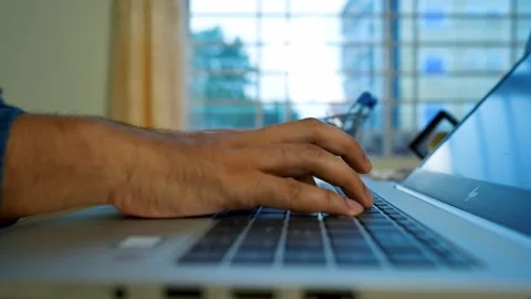 Close-up of hands typing on a laptop keyboard in a bright room Stock Footage 315981372