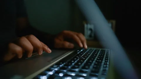 Close-up of hands typing on a laptop keyboard in a dimly lit room Stock Footage 315982498