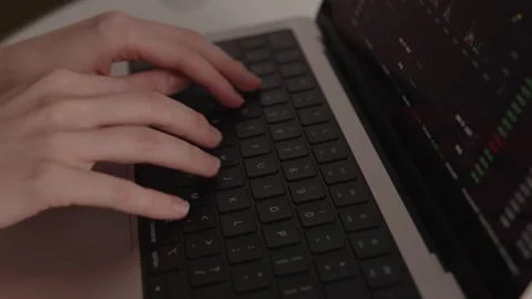 Close-up of hands typing on laptop keyboard while financial charts and digital Видео 317952023