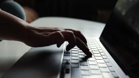 Close-up of hands typing on a laptop keyboard in soft, moody lighting Stock Footage 338998720
