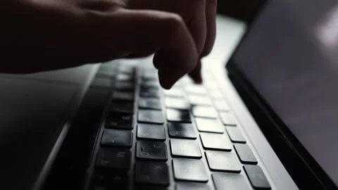 Close-up of hands typing on a laptop keyboard in dim lighting Stock Footage 338999065