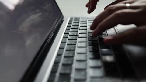 Close-up of hands typing on a laptop keyboard with screen reflections Stock Footage 338999252