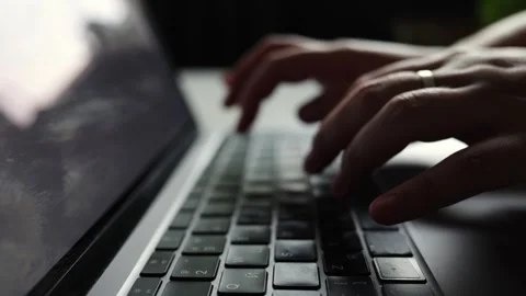 Close-up of hands typing on a laptop keyboard in dim lighting Stock Footage 338999297
