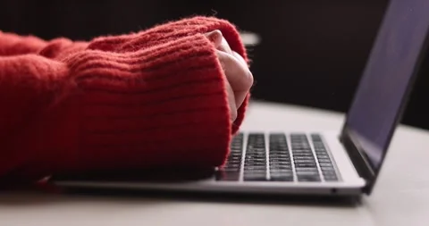 Close-up of hands typing on a laptop keyboard wearing a cozy red sweater Stock Footage 339072269
