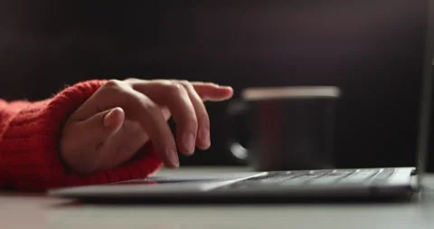 Close-up of hands typing on a laptop keyboard with a mug in the background Stock Footage 339072302