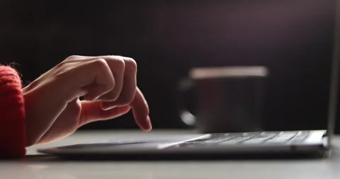 Close-up of hands typing on a laptop keyboard in a dimly lit room Stock Footage 339072577