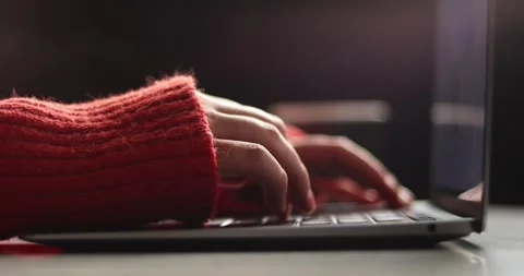 Close-up of hands typing on a laptop keyboard, wearing a cozy red sweater Stock Footage 339072783
