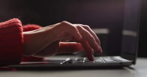 Close-up of hands typing on a laptop keyboard in a dimly lit room Stock Footage 339073463