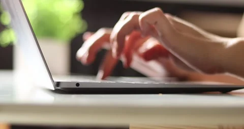 Close-up of hands typing on a laptop keyboard with a blurred green background Stock Footage 339074829