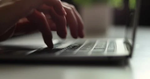 Close-up of hands typing on a laptop keyboard in a softly lit environment Stock Footage 339075248