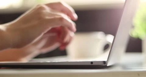 Close-up of hands typing on a laptop keyboard with a coffee cup nearby Stock Footage 339075449